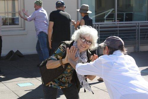 Two people dancing with their palms touching. In the background are three other people.