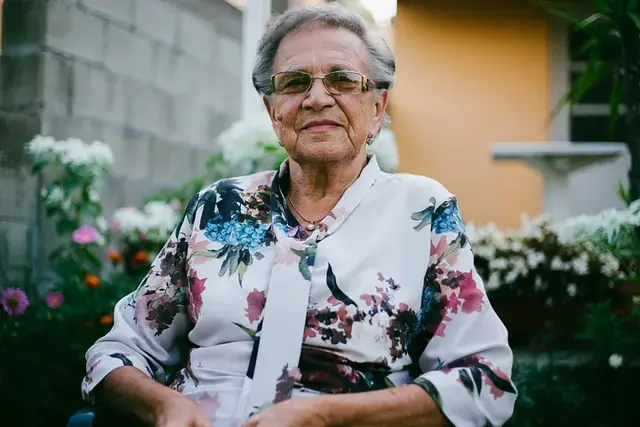 A woman wearing a colorful shirt with floral patterns and smiling slightly.